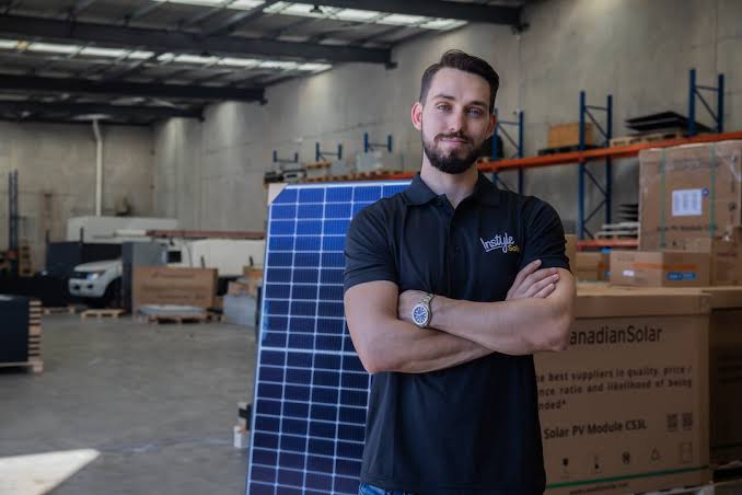 Standing beside a solar panel in the warehouse